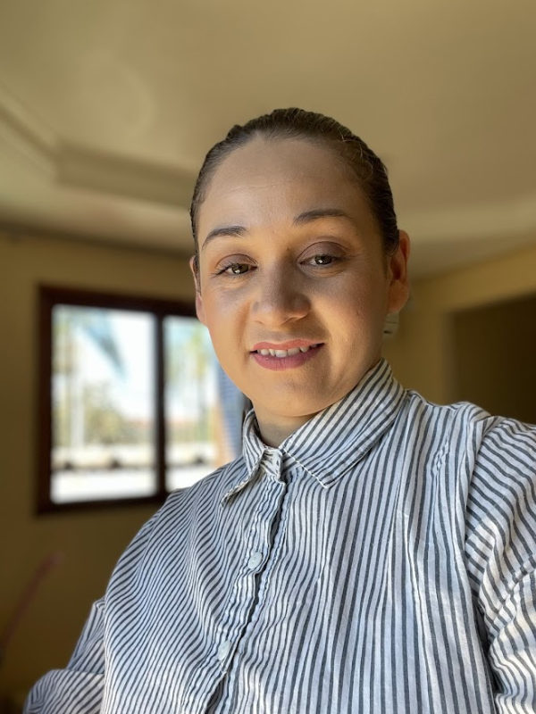 Confeiteira sorridente decorando um bolo em cozinha profissional bem iluminada